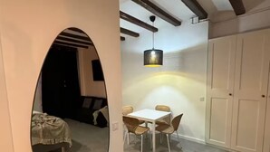 Una stanza con uno specchio rotondo, un tavolo da pranzo con sedie, una lampada a sospensione e un armadio.