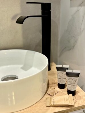 A bathroom with a white sink, black faucet, and two bottles of Green Tea Collection bath gel and shampoo on a wooden tray. - Premium Central appartment Las Ramblas: 4 Beds and baths, 9 guests (Barcelona)