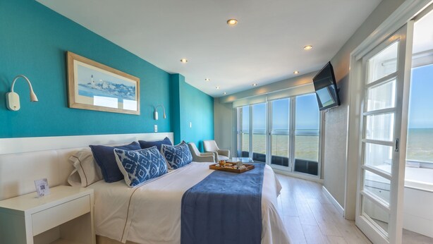Een slaapkamer met een bed, nachtkastje en een aan de muur bevestigde televisie.