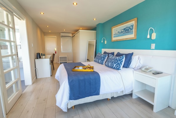 A bedroom with a bed, bedside table, and a desk with a chair. - HOTEL LAS ROCAS (Mar del Plata)