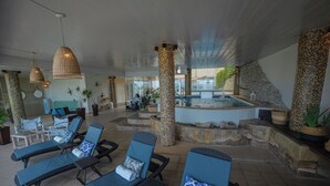 Een zwembadgedeelte met ligbedden, een jacuzzi en een trap naar een terras.