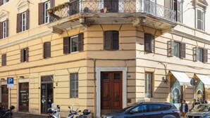 Un bâtiment avec une porte marron, une voiture garée et deux motos.