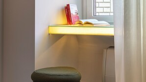 Un coin de pièce avec un bureau, une pile de livres et une chaise.