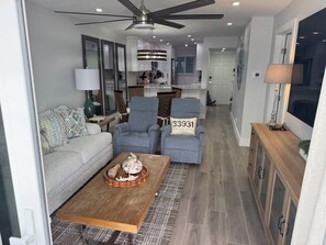 A modern living room with a sofa, two armchairs, a wooden coffee table, and a ceiling fan. - Beachfront Bliss! 2026 Rebuild - 2BR/2BA  - Weekly Rentals/Snowbirds Welcome! (Fort Myers Beach)