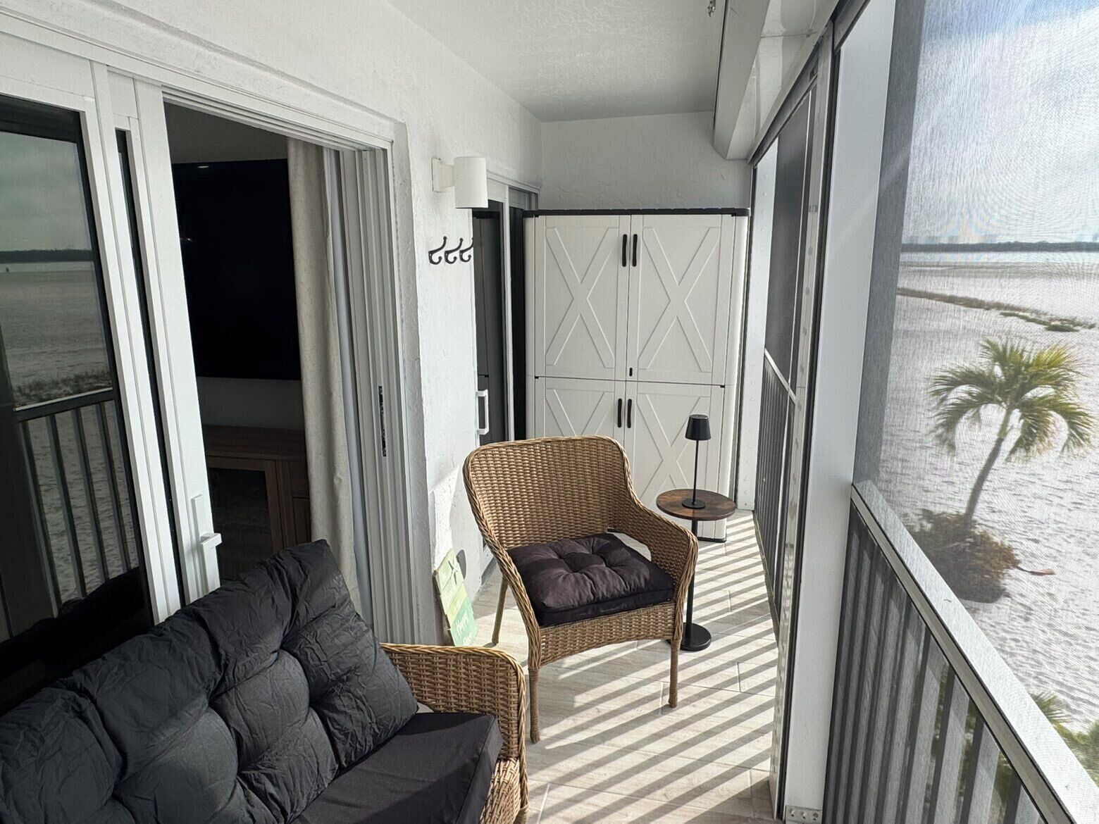 En balkon med en fletstol, et lille bord og en sofa.