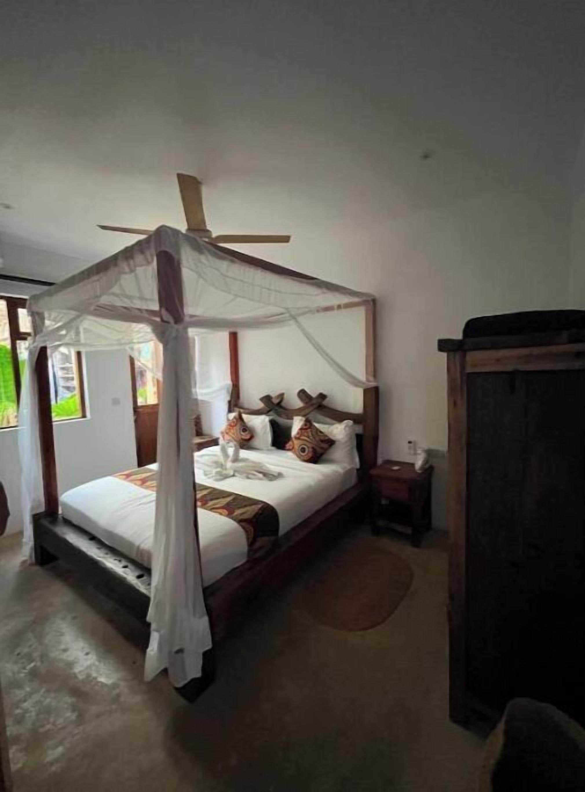 Une chambre avec un lit à baldaquin, une table de chevet en bois et une armoire.