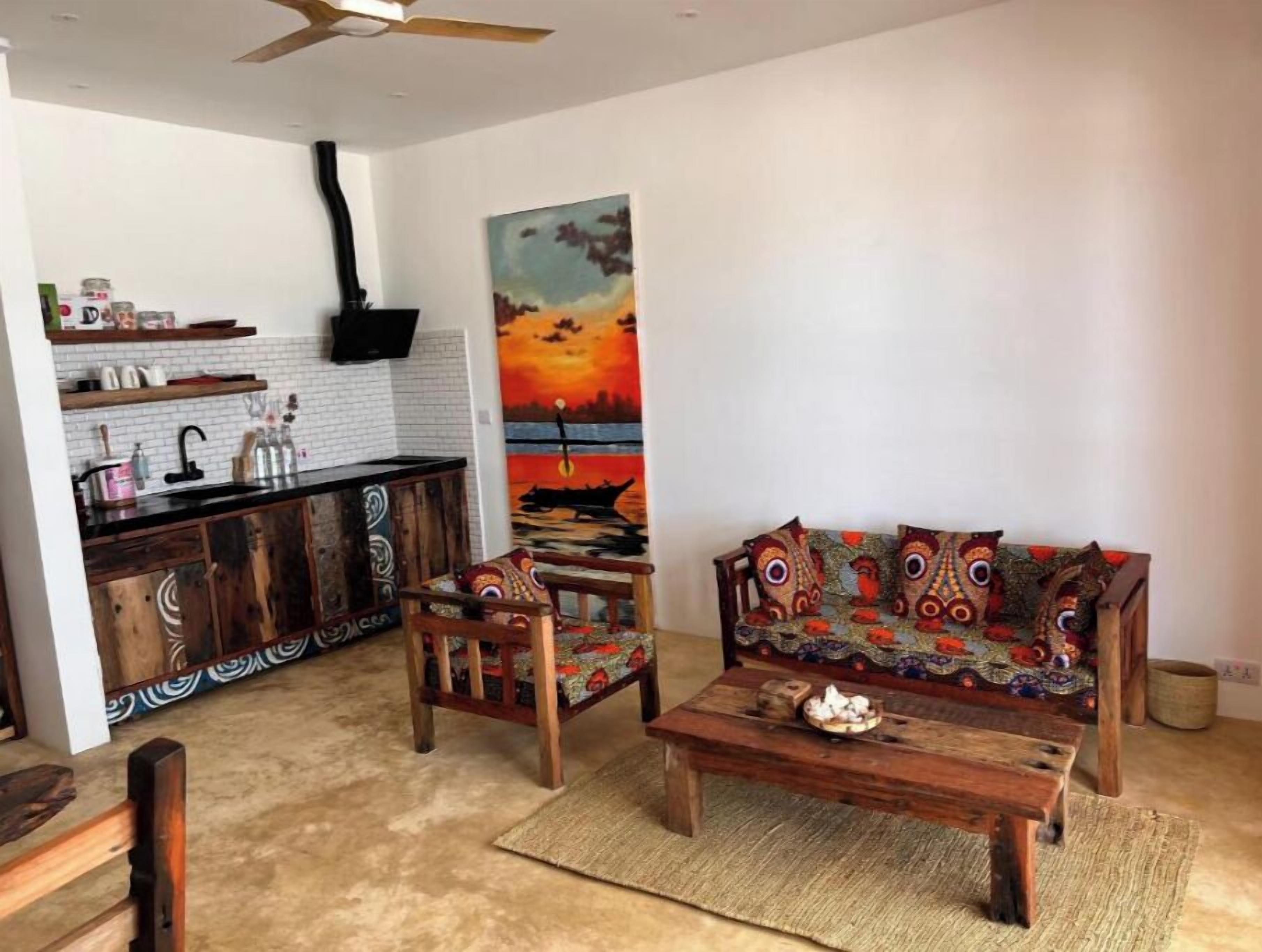 Una sala de estar con un sofá, una mesa de centro y un cuadro de un atardecer.