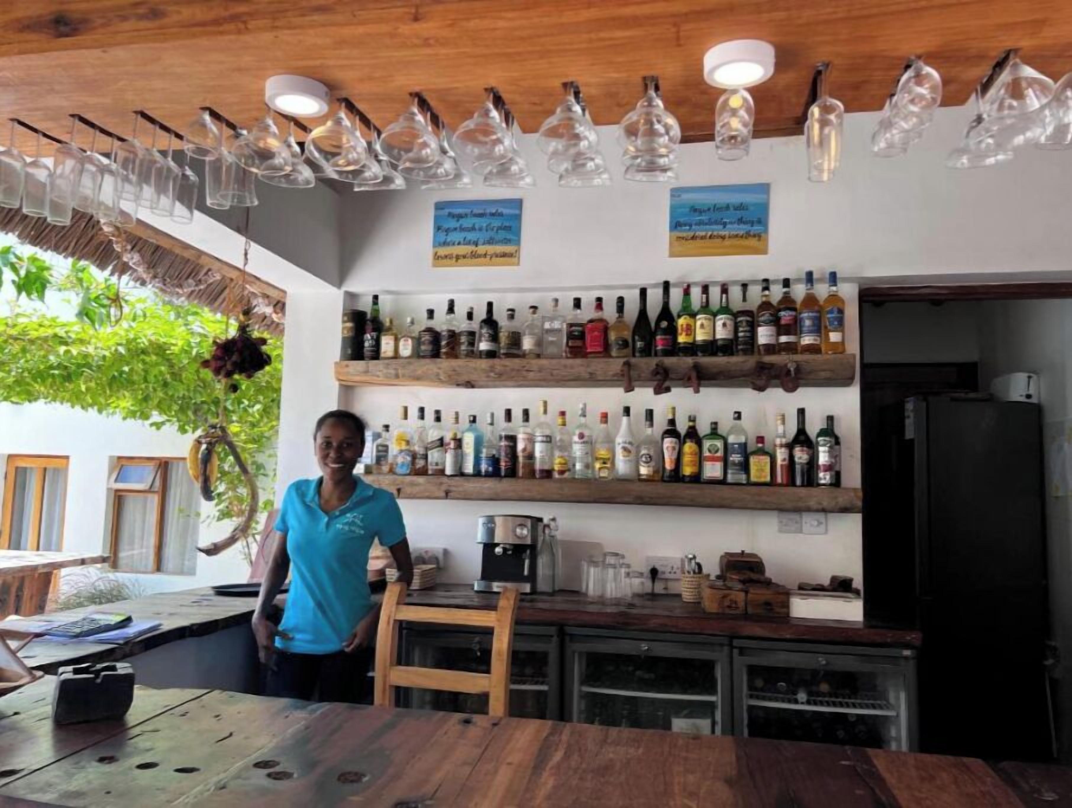 Eine Bar mit Holzböden, bestückt mit verschiedenen Spirituosenflaschen, einer Kaffeemaschine und hängenden Leuchten.