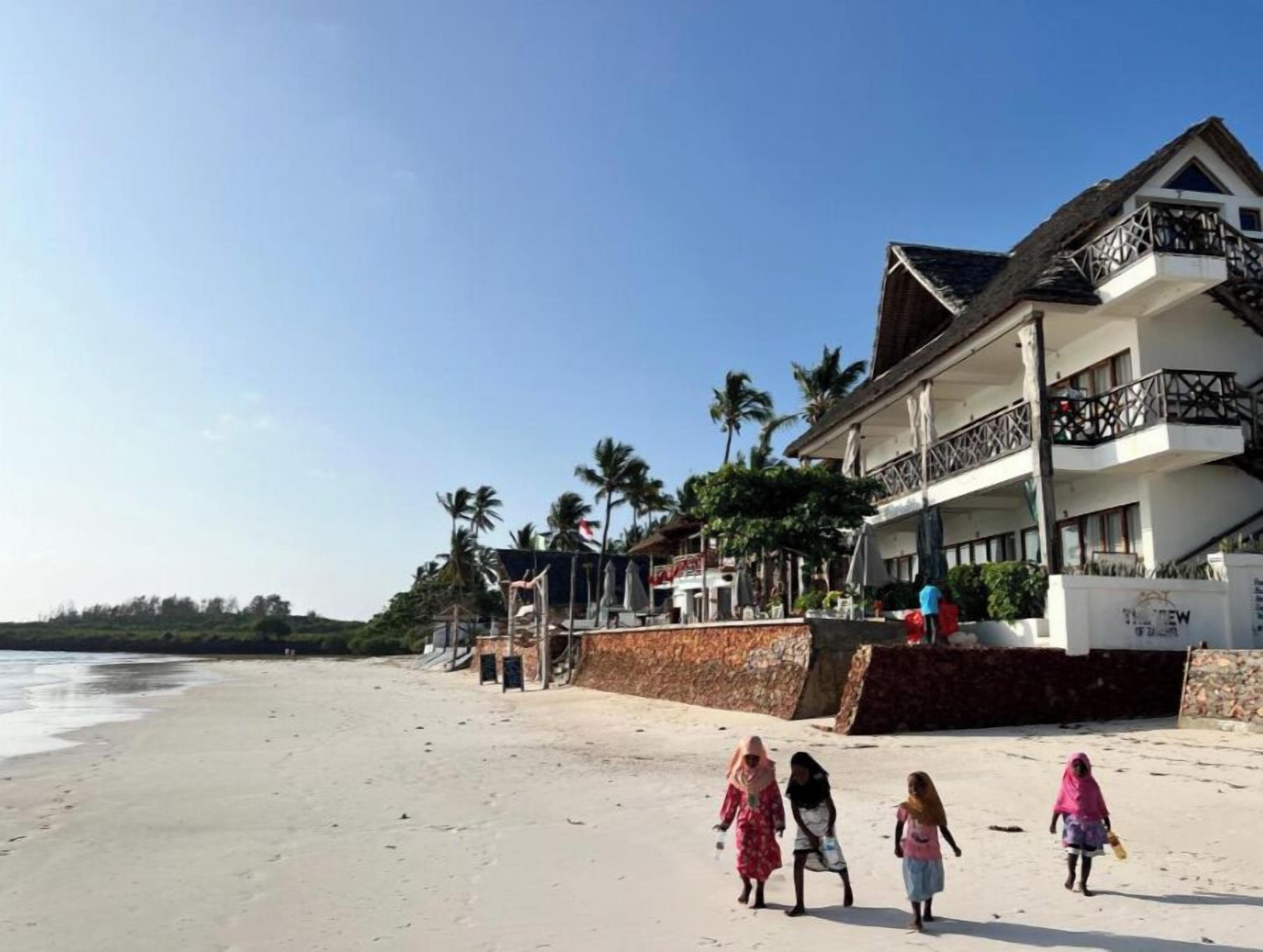 Una propiedad frente a la playa con un edificio grande, un balcón y vista al océano.