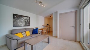 A modern living room with a grey sofa, a wooden coffee table, and a dining area in the background. - Moderne 2 Pieces Climatise Avec Terrasse A1b230 (Cannes)