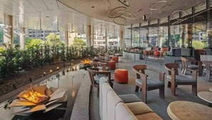 Uma área de estar moderna com lareira, assentos e grandes janelas com vista para o exterior.