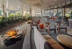 Ein moderner Lounge-Bereich mit Kamin, Sitzgelegenheiten und großen Fenstern mit Blick ins Freie.