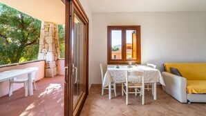 Uma área de refeições com mesa, cadeiras, um pilar de pedra e um sofá amarelo.