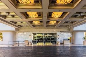 Ein Hotel mit modernem Design, das eine Glasfassade, eine Rezeption und eine strukturierte Decke zeigt.