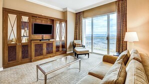 Ein geräumiges Wohnzimmer mit großem Flachbildfernseher, einer bequemen Couch, einem Glastisch und Blick auf die Stadt durch große Fenster.