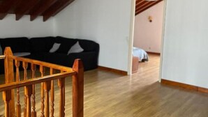 Una stanza con una scala in legno, un divano nero e un pavimento di legno.
