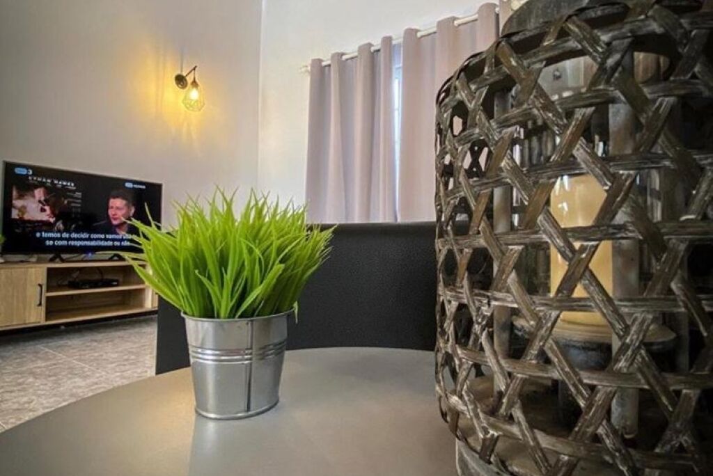 A living room with a television, a potted plant, and a decorative wall piece.
