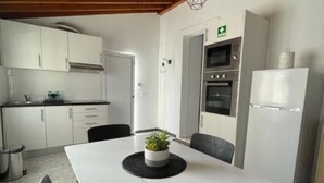 Una cucina moderna con mobili bianchi, forno integrato e frigorifero.