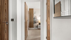 Un couloir avec des portes en bois et un miroir au mur.