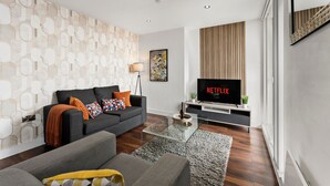Un salon moderne avec un canapé, une table basse et un téléviseur à écran plat.