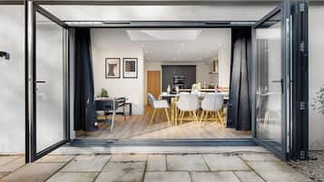 Een moderne keuken met donkere kastjes, een centraal eiland en een eethoek met een tafel en stoelen.