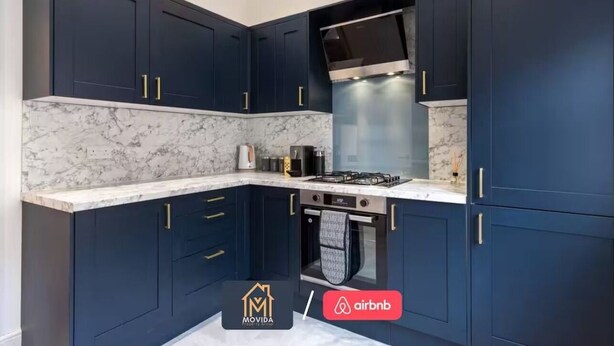 Uma cozinha moderna com armários azul escuro, fogão a gás e forno embutido.