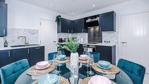Een moderne keuken met donkere kastjes, een roestvrijstalen afzuigkap en een marmeren spatwand.