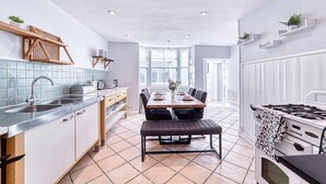 Eine moderne Küche mit Essbereich, ausgestattet mit einer zentralen Kochinsel, integrierten Geräten und Blick zum Esszimmer.