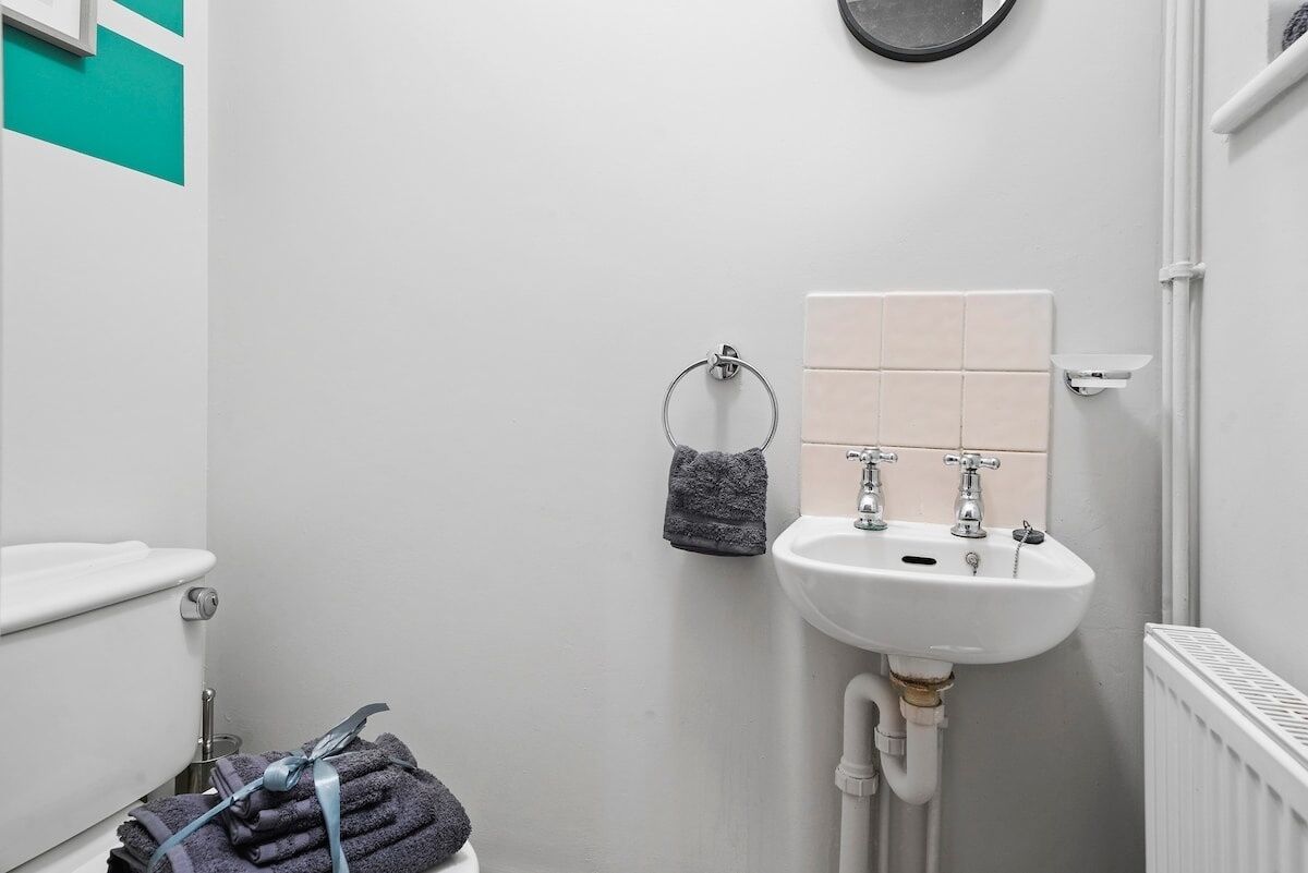A bathroom with a white sink, a towel rack with a folded towel, and a toilet.