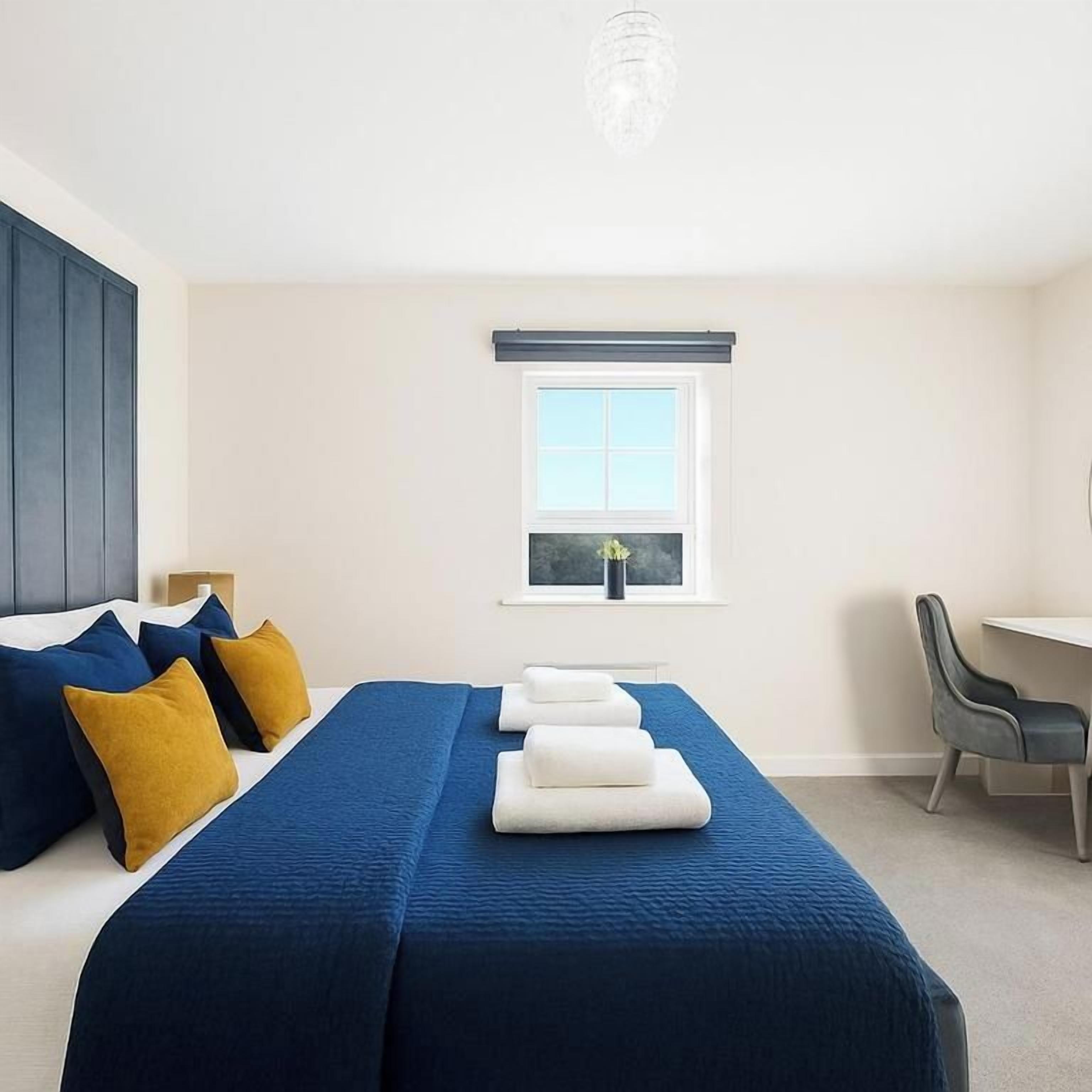 Ein Hotelzimmer mit Bett, Schreibtisch, Stuhl und Fenster.