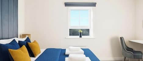 Ein Hotelzimmer mit Bett, Schreibtisch, Stuhl und Fenster.