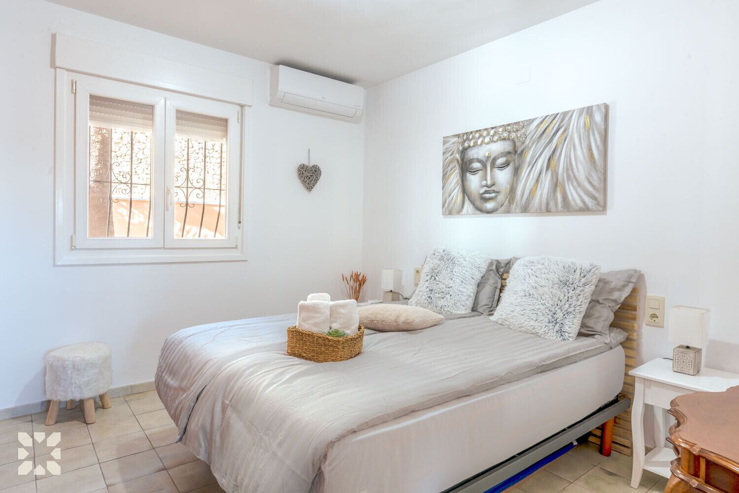 Une chambre à coucher comprenant un lit, une fenêtre, un climatiseur fixé au mur, une table de chevet et un élément décoratif mural.