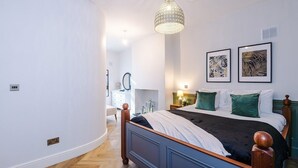 Un dormitorio con cama, lámpara de araña, obras de arte en la pared y mesita de noche.