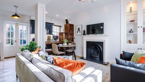 Una sala de estar moderna con chimenea, un comedor y una cocina al fondo.