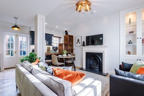 Ein modernes Wohnzimmer mit Kamin, Essbereich und einer Küche im Hintergrund.