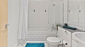 Een badkamer met douche, toilet en wastafel.