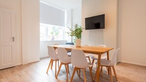 A dining area with a wooden table and six chairs, a potted plant, and a flat-screen TV mounted on the wall. - Comfort & Style in Salford - Sleeps 8 (Salford)