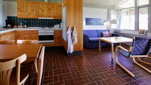 A compact kitchen with wooden cabinets, a stove, and a dining area with a table and chairs. - 3 Rooms, Standard, 4+1 People, 68m2 (Karrebæksminde)