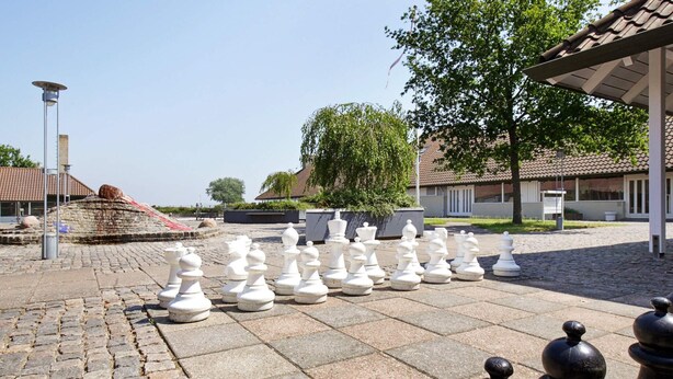 A courtyard with a chessboard setup, cobblestone pavement, and a building with a tiled roof in the background. - 3 Rooms, Standard, 4+1 People, 68m2 (Karrebæksminde)