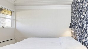 A neatly made bed with white bedding in a room with white walls and a window. - 3 Rooms, Standard, 4+1 People, 68m2 (Karrebæksminde)