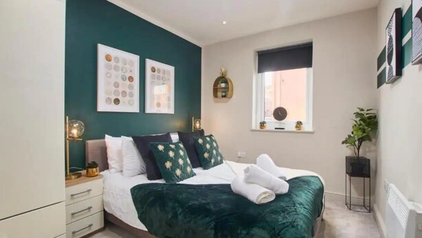 Een moderne slaapkamer met een bed, nachtkastjes, een raam en wanddecoratie.