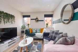 Un salon moderne avec un téléviseur à écran plat, un canapé, une table basse et un grand miroir.
