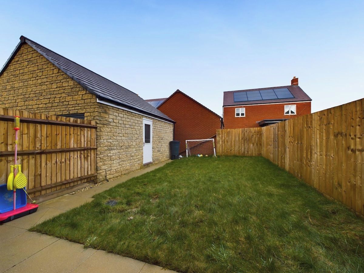A residential backyard with a stone building, a wooden fence, and a grassy lawn.