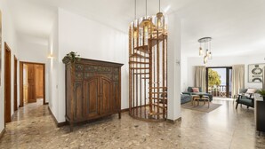 Un vaste espace de vie comprenant un meuble en bois, un escalier en colimaçon et un coin salon avec un canapé et une table basse.