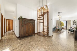 A spacious living area with a wooden cabinet, a spiral staircase, and a seating area with a sofa and coffee table. - Villa Santa Rosa La Peñita by Escape Home (Puerto del Carmen)