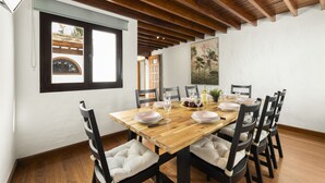 Un coin repas avec une table en bois dressée pour quatre personnes, entourée de chaises rembourrées.