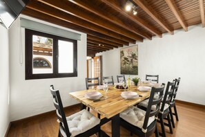A dining area with a wooden table set for four, surrounded by upholstered chairs. - Villa Santa Rosa La Peñita by Escape Home (Puerto del Carmen)