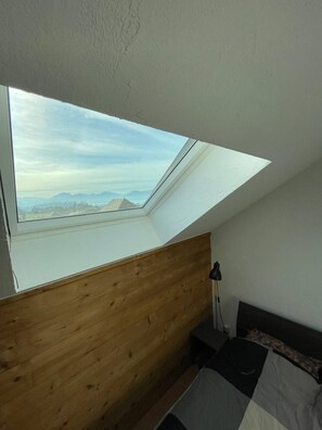 A bedroom with a skylight, wooden headboard, and a bed with a patterned bedspread. - Bright duplex with terrace and lake view – Brison-Saint-Innocent (Brison-Saint-Innocent)