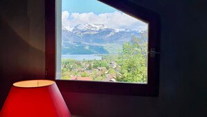 A window with a view of a lake, mountains, and a village.