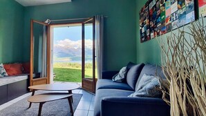 A living room with a sofa, a coffee table, and a view of mountains through a glass door.